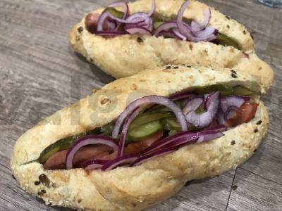 Karštas šuo su dešrele ir raudonuoju svogūnu grūdų bandelėje pagrindine nuotrauka