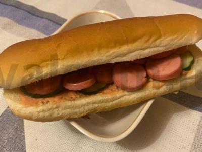 Karštas šuo „Apskritimai“ su dešrele, agurku ir džiovintų daržovių prieskoniu pagrindine nuotrauka