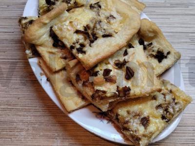 Pica su baltais grybais ant paruošto sluoksniuoto tešlos pagrindine nuotrauka