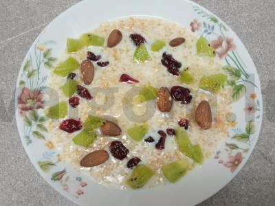 Pieninė košė iš kvietinių kruopų su kokosų aliejumi, džiovintomis spanguolėmis, migdolais, kiviais ir cukranendrių cukrumi pagrindine nuotrauka