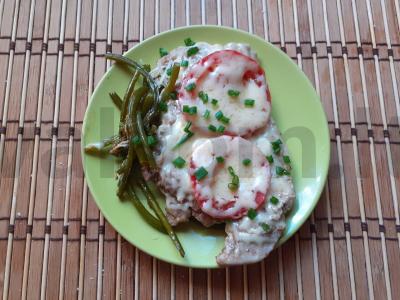 Kiaulienos steikas su pomidorais, sūriu ir česnako stiebais pagrindine nuotrauka